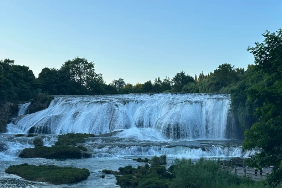 Wide tranquil waterfall surrounded by lush green karst scenery