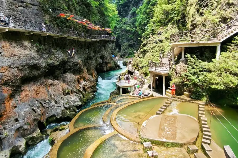 Primitive karst canyon with steep cliffs, emerald streams and hanging cliff walkways