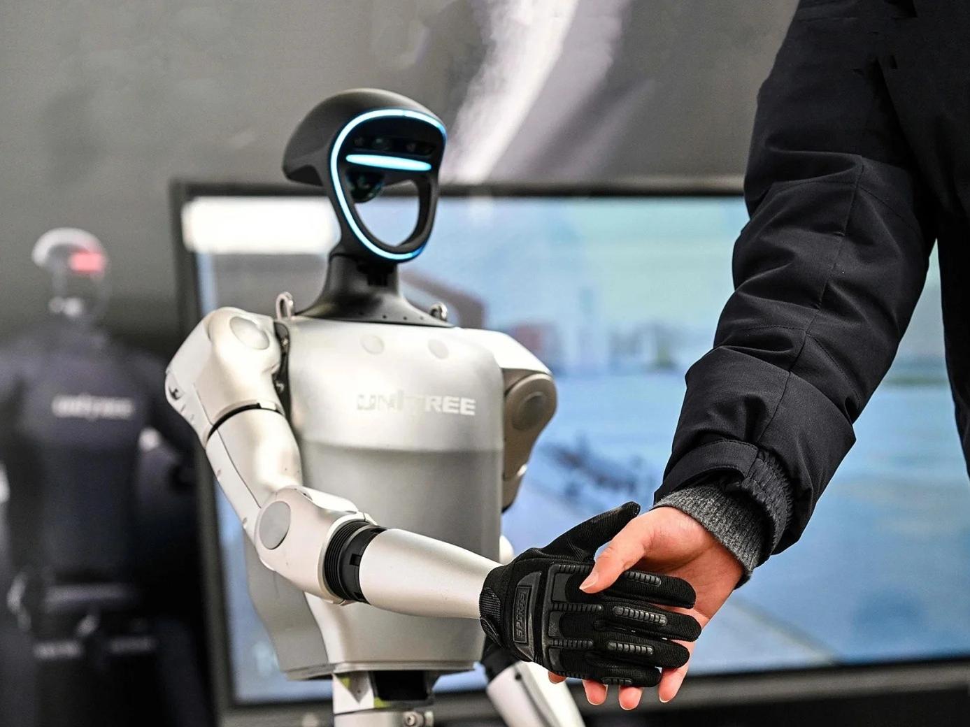 Close?up shot of Unitree humanoid robot shaking hands with a person at technology exhibition