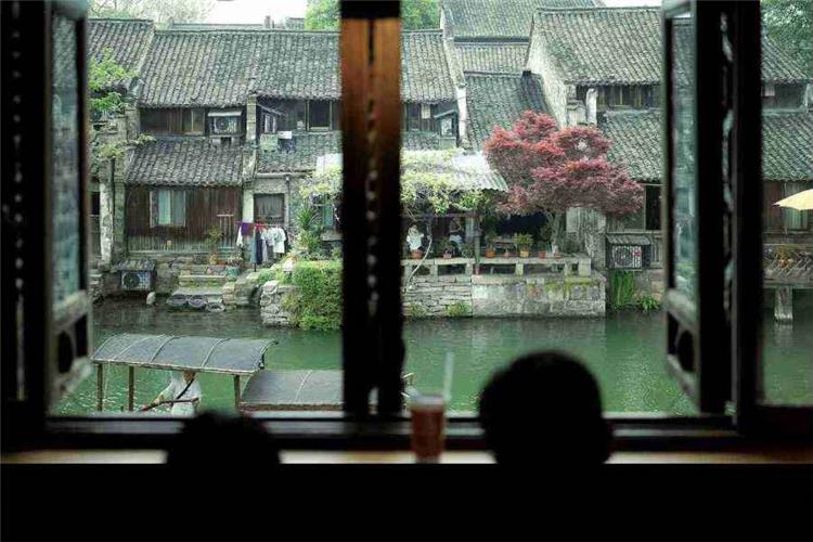 Traditional Jiangnan water town scenery viewed through wooden window, ancient houses and calm canal in Wuzhen
