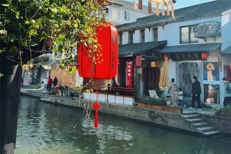 Riverside old teahouse in Anchang Ancient Town Shaoxing featuring wooden waterfront house, bamboo chairs, steaming tea sets and tranquil canal water town scenery outside carved windows