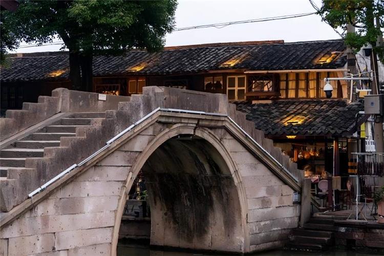 Quiet ink-wash style Jiangnan scenery of Anchang Ancient Town, clear river reflecting white-wall black-tile buildings, drifting black-awning boats and winding covered verandas along waterways
