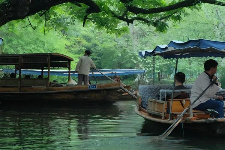 Leisurely boating on West Lake Hangzhou, classic wooden painted pleasure boats gliding over mirror-like lake water surrounded by green hills, willow causeways and ancient pagodas1000 Place...
