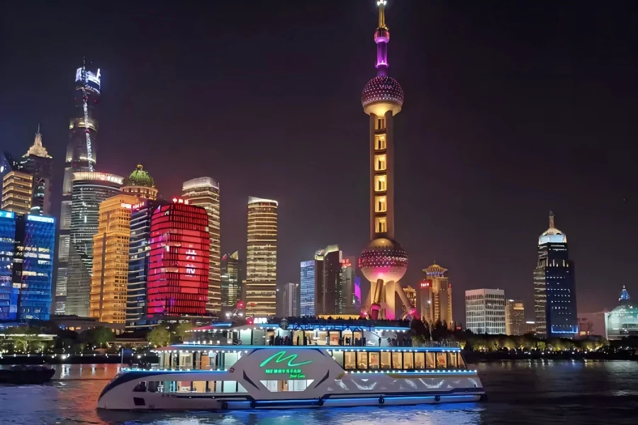 The Bund Night Cruise in Shanghai showing illuminated sightseeing ships sailing on Huangpu River, with glowing colonial buildings of The Bund and dazzling Pudong skyscraper night skyline on both river banks