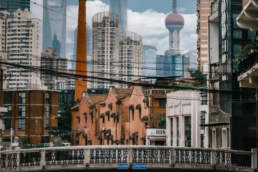 No.2 Harbin Road Bridge in Shanghai showing vintage riverside factories paired with distant Lujiazui skyscrapers over Shajinggang Creek