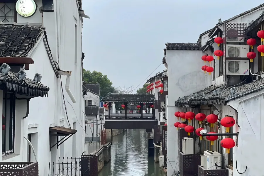 Daytime Waterside View of Ancient Gusu Shantang Qili Shantang Canal in Suzhou, featuring Ming and Qing waterside dwellings, stone arch bridges and wooden tourist boats floating on tranquil canal waters
