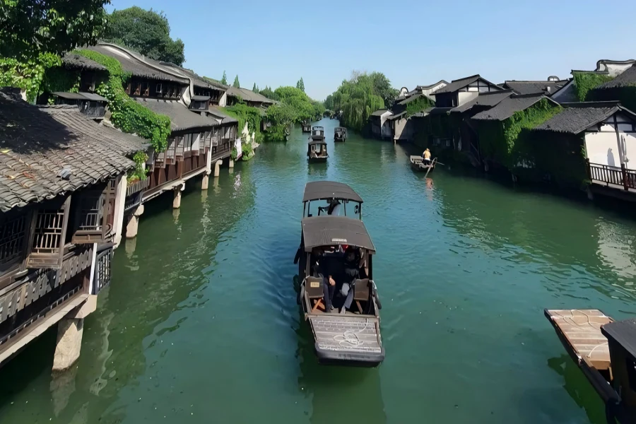 Wuzhen Ancient Water Town in Jiaxing, home to world internet conference venue, featuring stilted riverside dwellings, stone arch bridges and gliding black-awning boats amid peaceful canal networks