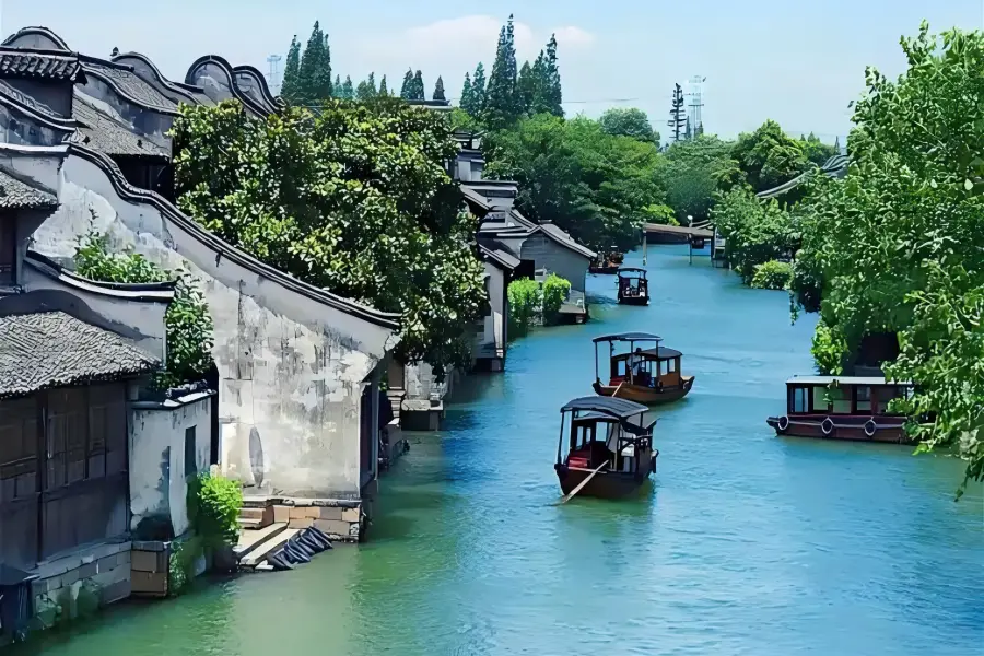Xitang Ancient Water Town featuring compact labyrinthine narrow lanes, well-preserved Ming and Qing waterfront dwellings, glowing red lanterns reflecting on calm canal waters at dusk