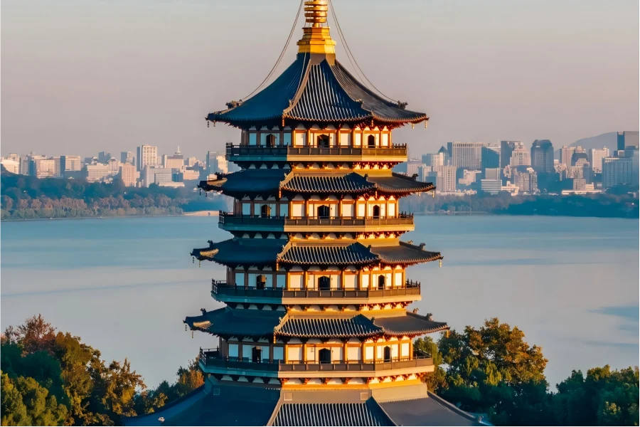 Leifeng Pagoda in Hangzhou overlooking shimmering West Lake under warm sunset glow