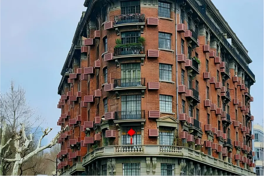 Historic Wukang Mansion Century-old Normandie Apartments with red brick facade, standing at the crossroads shaded by lush plane trees