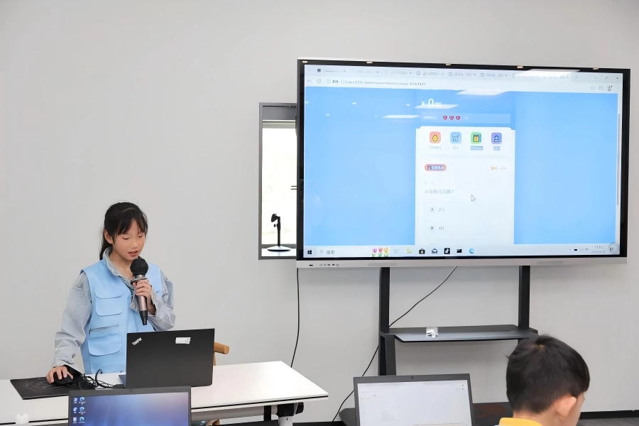 Student giving speech with microphone, demonstrating AI project results on large screen