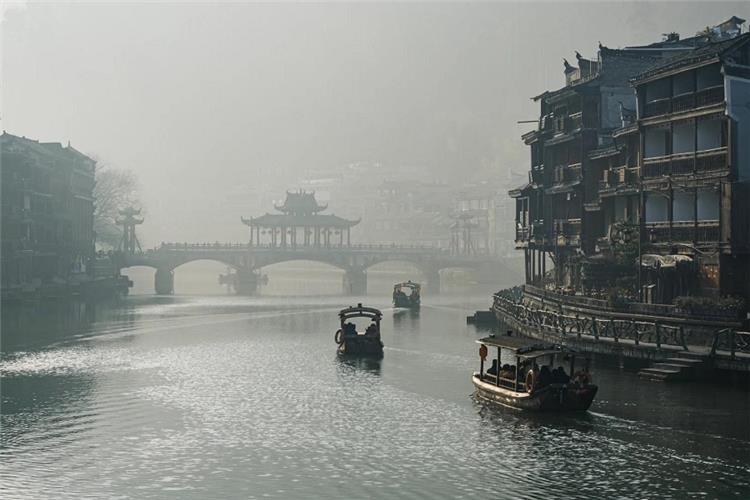 Misty River Cruise Fenghuang Ancient Town Wooden tourist boats on misty Tuojiang River at dawn, Fenghuang water town