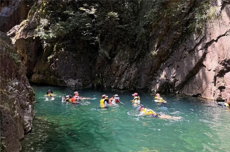 Group of tourists with life vests swimming and canyoning in emerald?green canyon water at Beijing Heilongtan