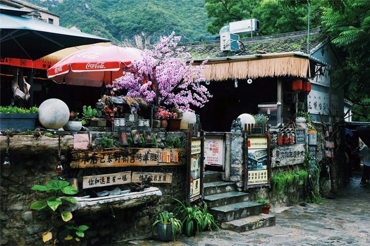 Vintage local storefront along stone street with decorative plants and wooden signs in Cuanxia Village