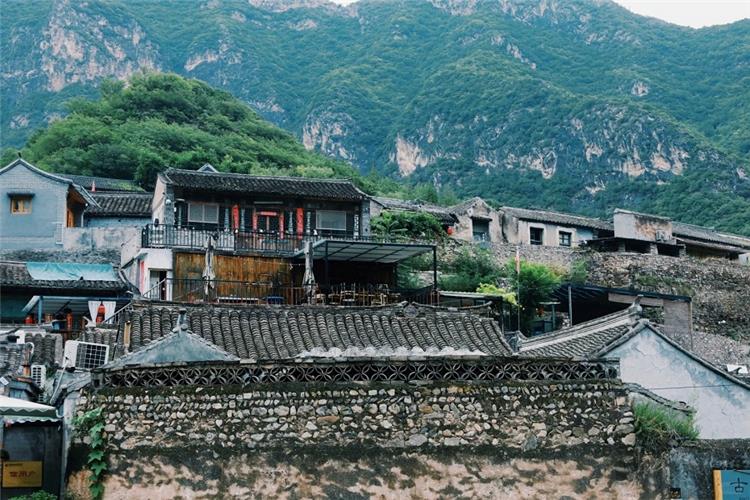 Traditional stone?built courtyard houses of Cuanxia ancient village against green mountain backdrop