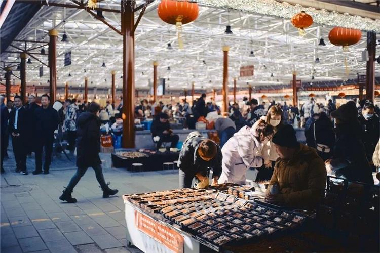 Spacious covered hall of Panjiayuan market, crowds of shoppers wandering among antique and craft vendor booths