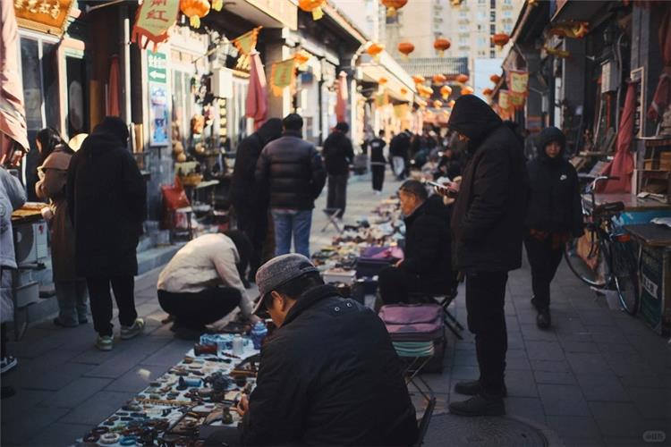 Bustling street view of Panjiayuan flea market, vendors and visitors browsing antiques and handicraft stalls under red lanterns