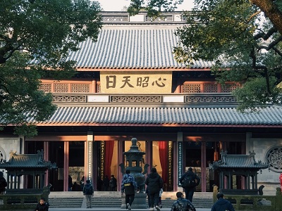 Ancient main hall of Yuefei Temple framed by green trees with golden plaque, Hangzhou historic memorial site