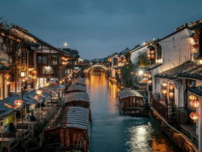 Night scenery of Shantang Ancient Street in Suzhou, canal with covered boats, lantern-lit white-walled houses and stone arch bridge