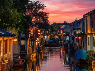 Dusk scenery of Zhouzhuang ancient water town, pink sunset sky, red lanterns, stone arch bridge and canal house reflections on water