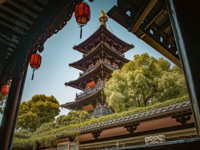 Ancient multi-story pagoda of Hanshan Temple framed by wooden eaves and red lanterns, Suzhou historic temple scenery
