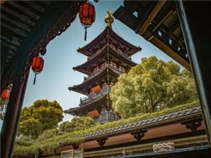Ancient multi-story pagoda of Hanshan Temple framed by wooden eaves and red lanterns, Suzhou historic temple scenery