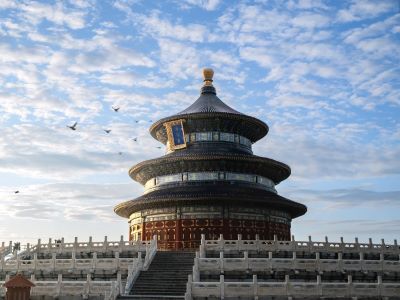 Ancient Chinese architecture of Temple of Heaven in Beijing, three-tier circular roof under blue sky with flying pigeons