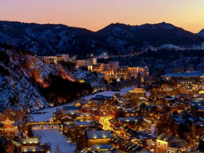 Overlook of illuminated ancient Gubei Water Town with snow-covered mountains at sunset dusk