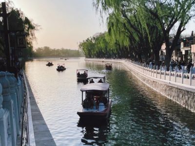 Pleasure boats cruising on Shichahai lake, weeping willows along the riverside at dusk