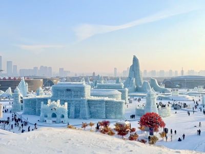 Giant ice castles and ice sculptures at Harbin Ice and Snow World, snow ground with tourists under clear sky