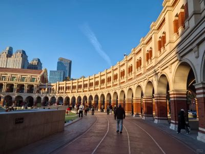 Curved arc corridor European architecture of Tianjin Five Avenues, tourists strolling under clear blue sky