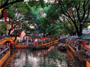 Canal with warm light, red lanterns, stone arch bridge and wooden boats at Tongli Ancient Town in Suzhou