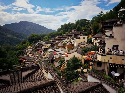 Terraced Hui-style ancient houses stacked on hills of Huangling Village, green mountain ranges and blue sky with white clouds in Wuyuan Jiangxi