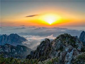 Golden sunrise glowing above layered sea of clouds, jagged granite peaks and pine trees of Huangshan Mountain, stunning alpine dawn scenery