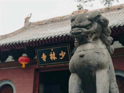 Ancient stone lion in front of Shaolin Temple main gate with traditional Chinese architecture