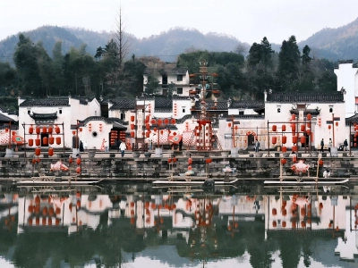 Huizhou-style white wall black tile buildings in Chengkan Village, red lanterns along the river