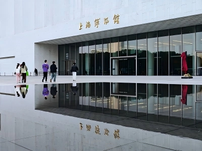 Modern minimalist building of Shanghai Museum, walking visitors, golden Chinese name sign on white wall