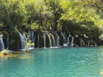 Beautiful waterfall flowing into a turquoise lake surrounded by lush forests in Jiuzhaigou National Park