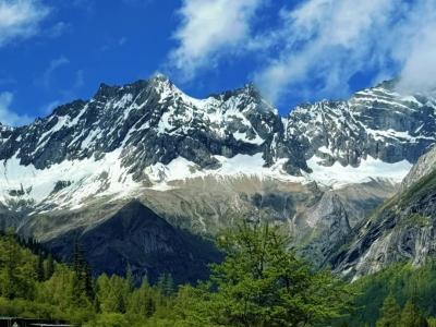 Xiling Snow Mountain and green grassland scenery on a sunny day