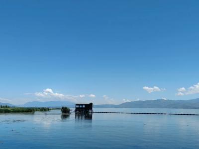 Beautiful Erhai Lake scenery in Dali featuring calm water, a small boat, clear blue sky, and distant mountains