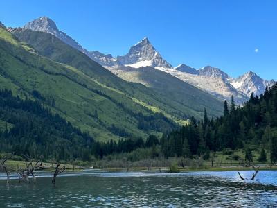 Four Sisters Mountain scenery with snow peaks, forest, and alpine lake in Sichuan