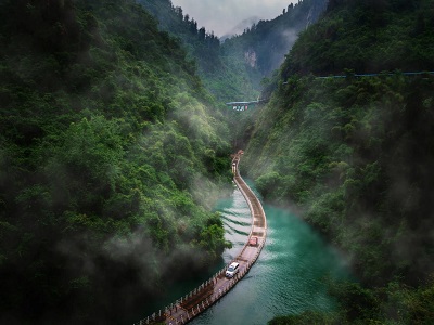 Shiziguan Floating Bridge in Enshi with a winding water walkway, turquoise river, misty mountains, and lush forest scenery