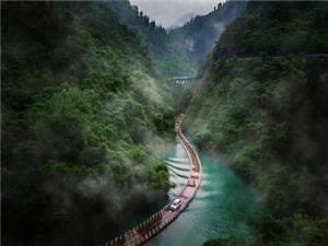 Shiziguan Floating Bridge in Enshi with a winding water walkway, turquoise river, misty mountains, and lush forest scenery