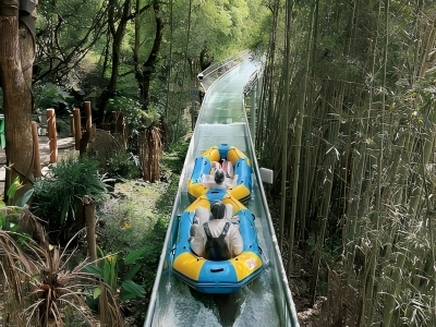 Visitors riding raft on mountain water slide surrounded by bamboo and woods at Heartbeat Paradise