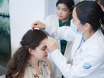 Foreign tourists experience traditional Chinese medicine acupressure massage at a Beijing TCM clinic