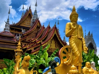 Golden Buddha statue and traditional Dai-style temple architecture at Xishuangbanna General Buddhist Temple