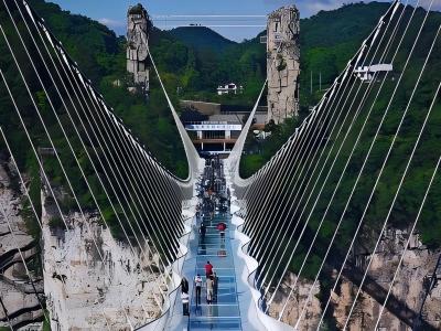Zhangjiajie Grand Canyon Glass Bridge suspended between mountains with visitors walking above the canyon
