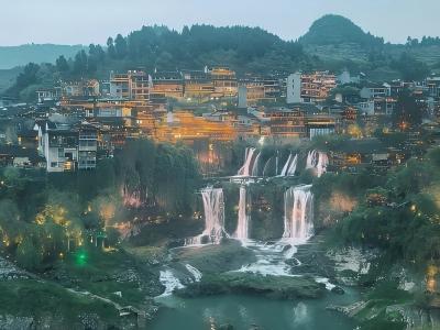 Furong Ancient Town built above a waterfall with traditional buildings and illuminated scenery