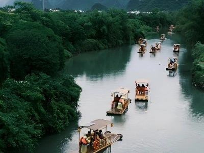 Bamboo rafts sailing on Yulong River, lush green trees and karst mountains on both sides