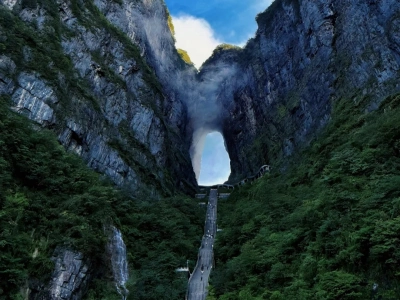 Giant natural cave Tianmen Cave, steep cliff stairway, towering rocky cliffs and lush forest, Hunan China